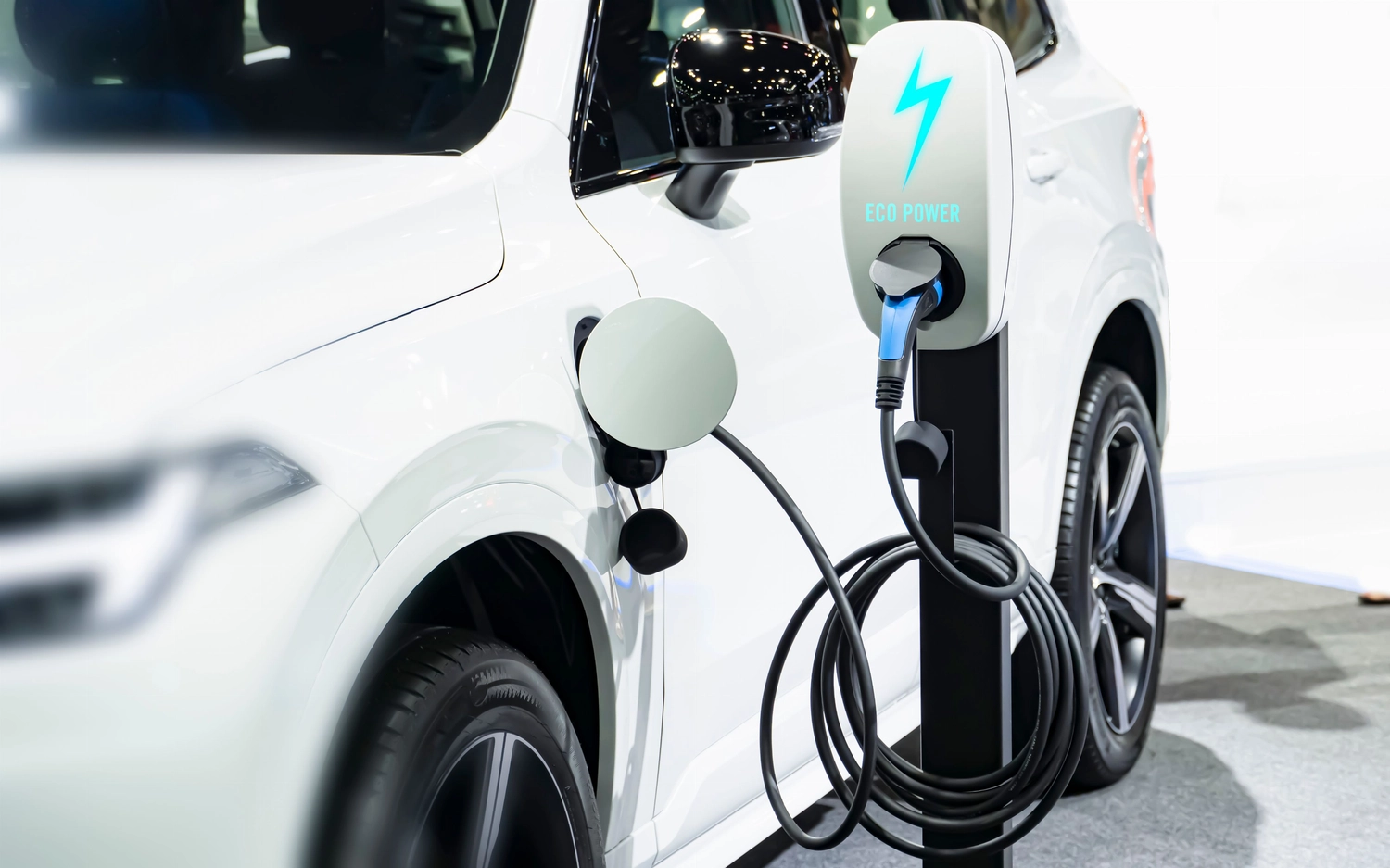 SVH Sachverständigenbüro – Automobilexperte – ein Elektrofahrzeug (EV), das an eine Ladestation angeschlossen ist und den Wandel der globalen und lokalen Automobilindustrie hin zu nachhaltigem Transport repräsentiert